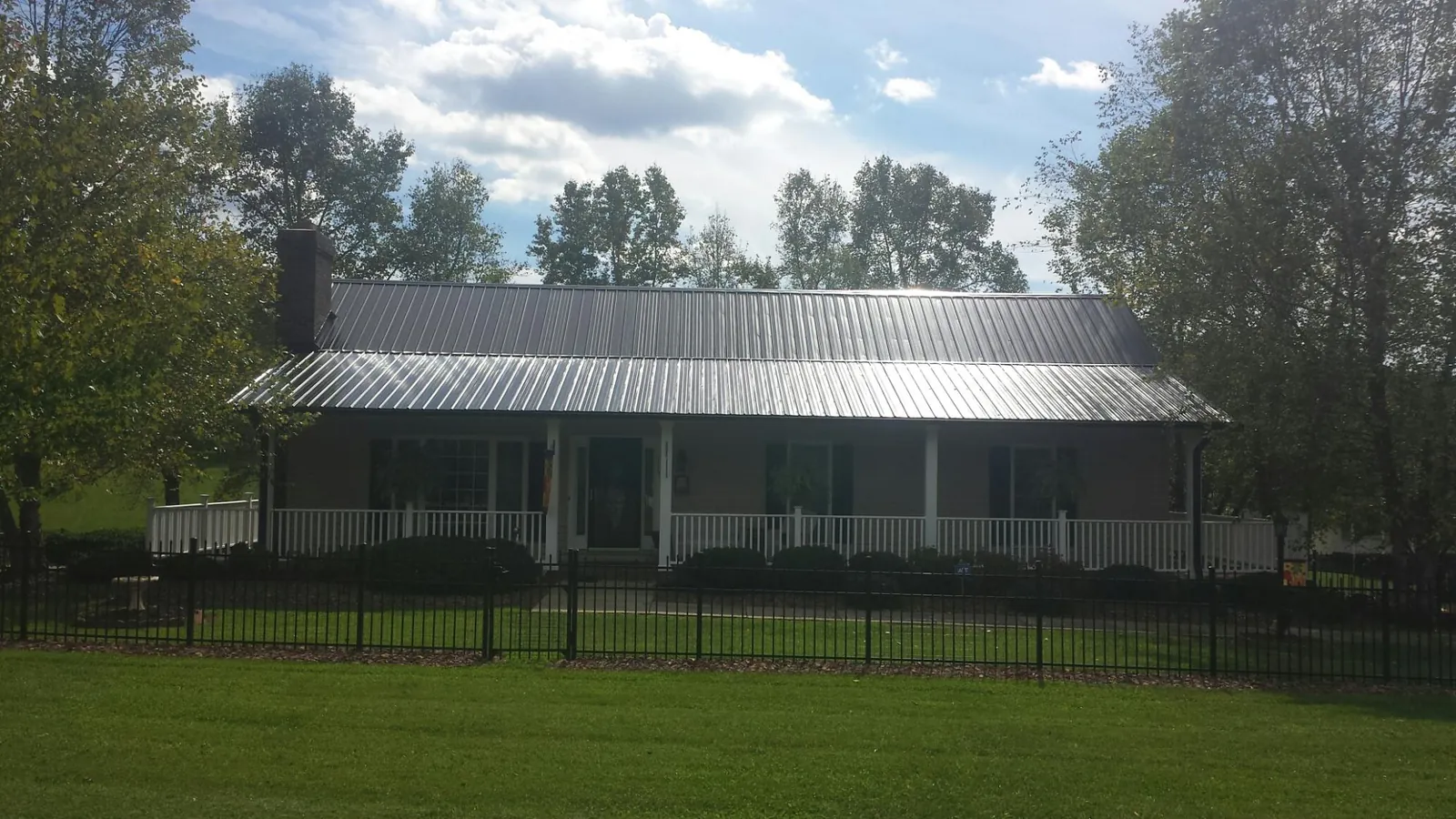 Gray metal roof on a brick ranch with a full width front porch — Gutter Guard Installation work by our crew in Tabor City