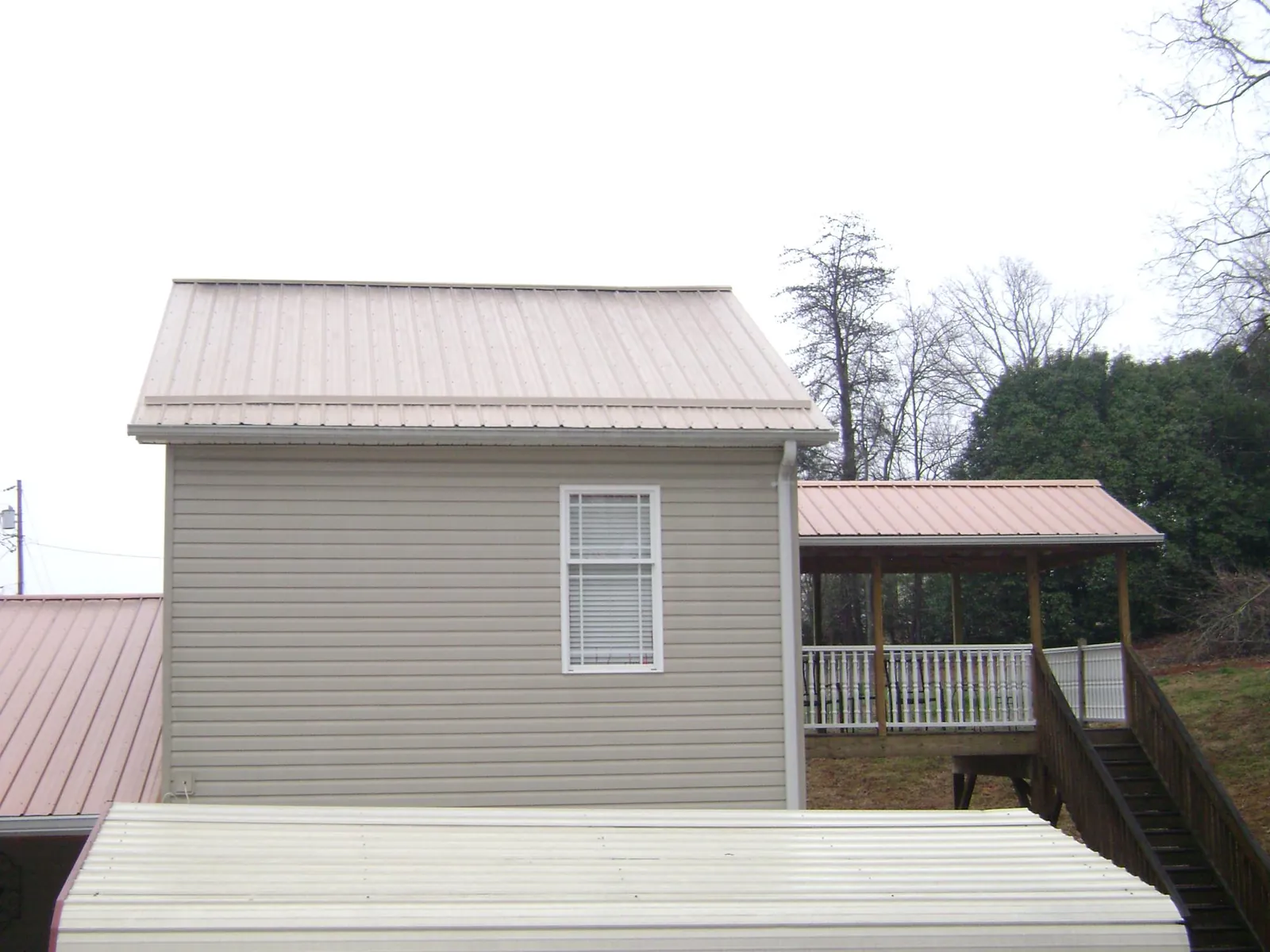 Tan metal roofs on a two story addition and attached porch, from a Roof Replacement job in Tabor City